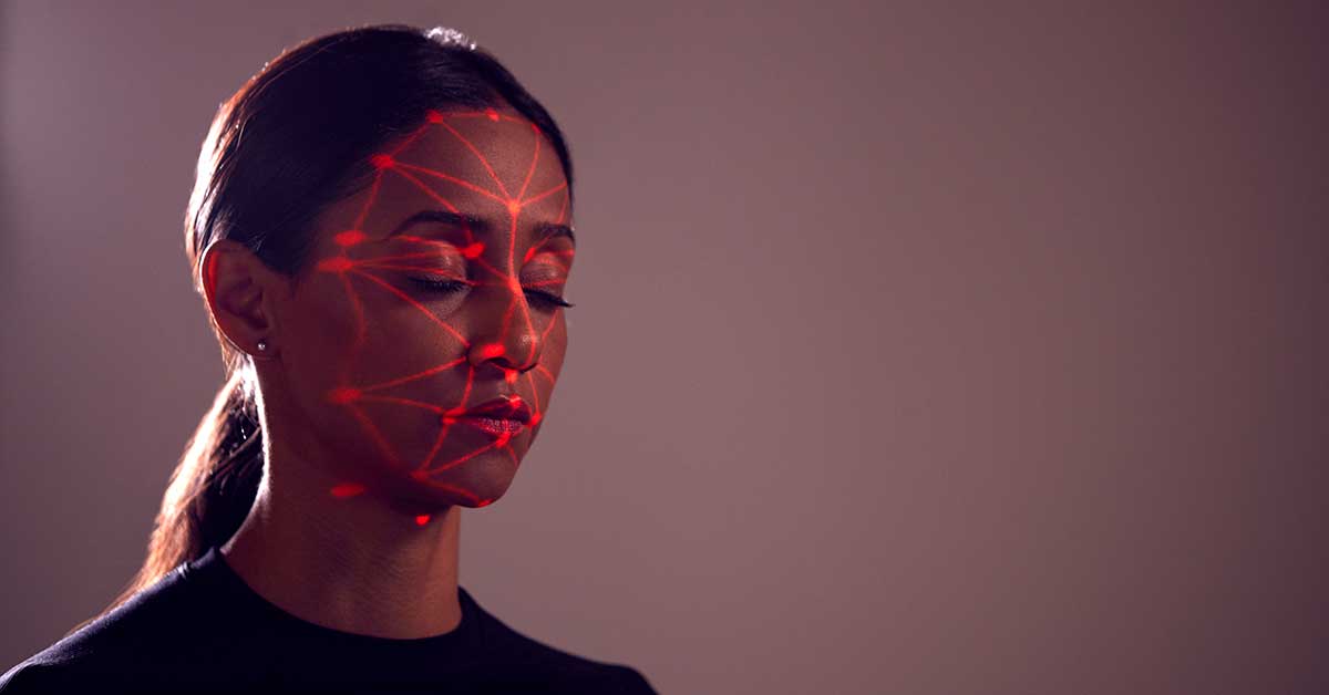 A woman with eyes closed, her face illuminated by a red geometric pattern, evokes intriguing implications.