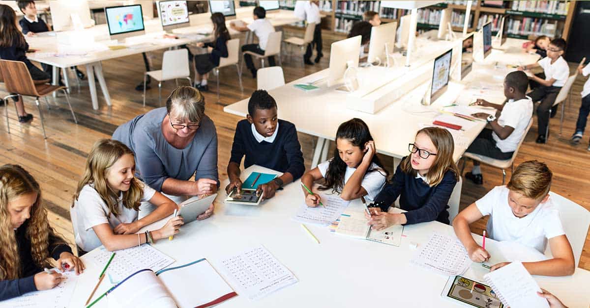 Students engage in personalized learning, working with a teacher on tablets and notebooks, while computers in the background showcase AI-driven instruction.