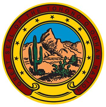 The Great Seal of the Tohono O'odham Nation, featuring a desert landscape with a mountain, cactus, and foliage, encircled by a yellow ring with stars and text.