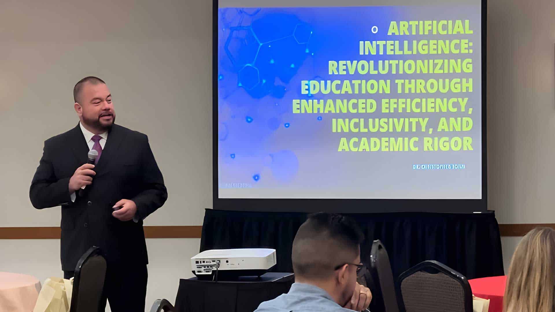 A man in a suit is giving a presentation titled "Artificial Intelligence: Revolutionizing Education Through Enhanced Efficiency, Inclusivity, and Academic Rigor" to a seated audience.