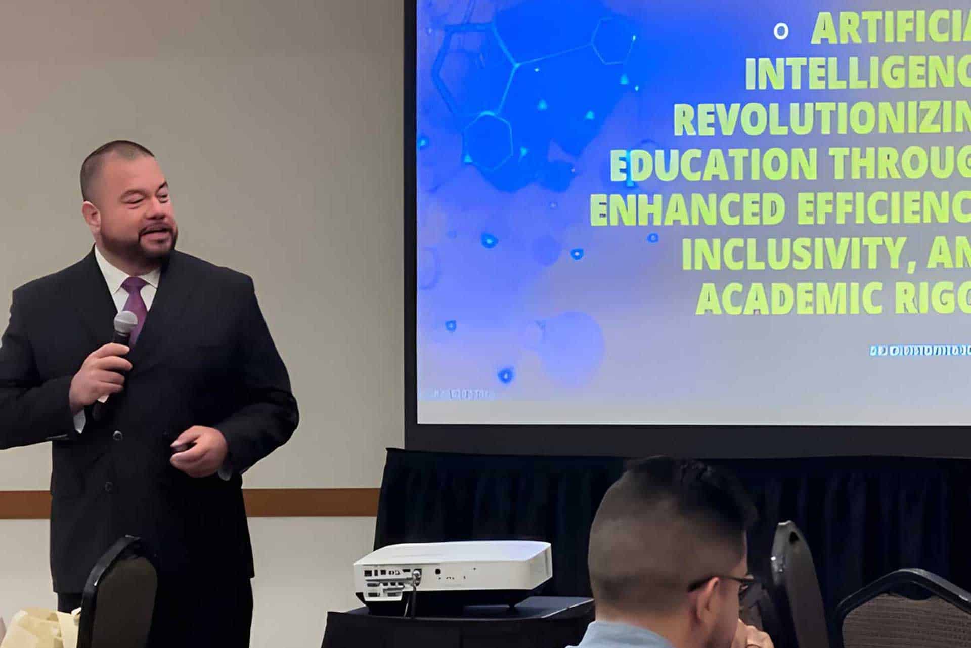 A man in a suit holds a microphone while standing next to a projection screen displaying a presentation on artificial intelligence in education, drawing parallels with executive coaching strategies. Audience members are seated facing the screen.